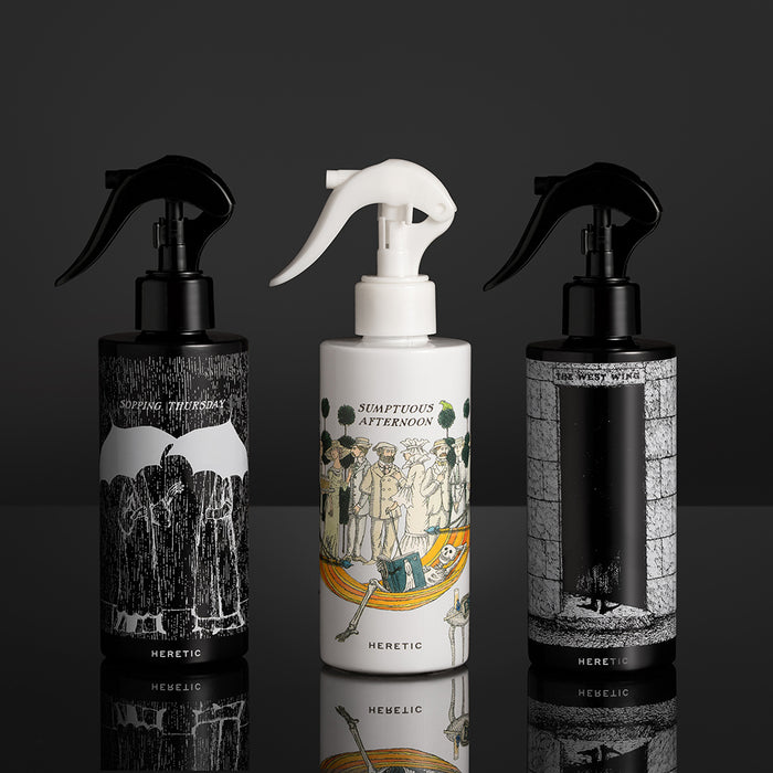 Three spray bottles with artistic labels on a dark background