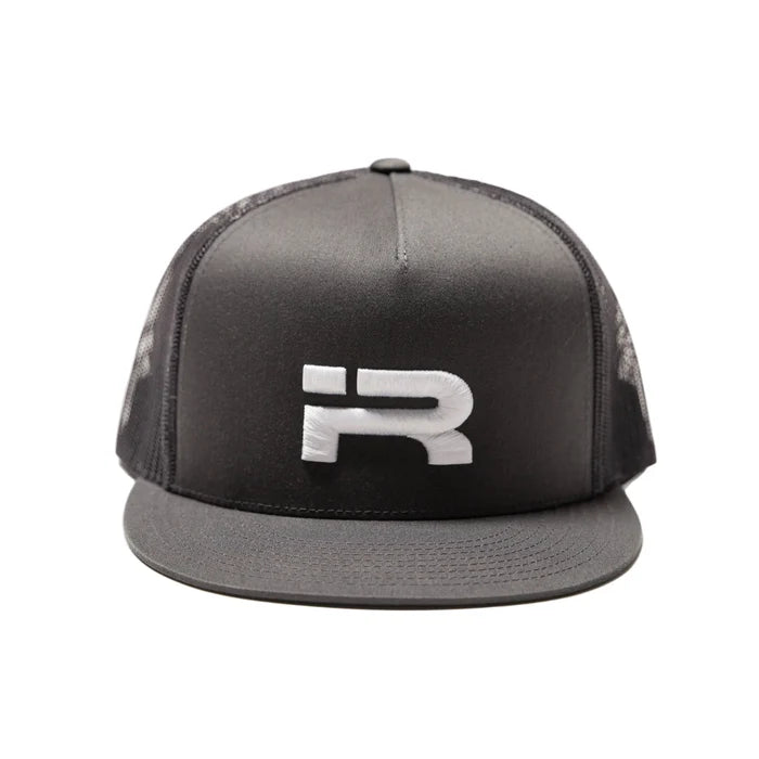 A charcoal trucker-style cap with a structured front panel, black mesh back, and a flat brim, featuring a large white stylized 'R' logo on the front. The cap is photographed against a clean, light off-white studio background.