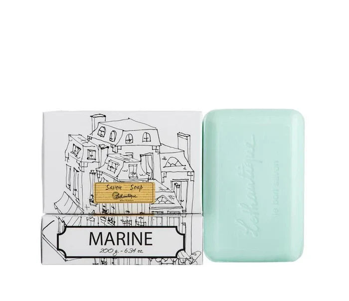 A white box of Lothantique bar soap with a drawing of a cityscape and labelled with the scent Marine, beside a light blue bar of soap.