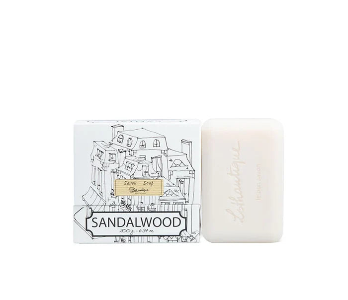 A white box of Lothantique bar soap with a drawing of a cityscape and labelled with the scent Sandalwood, beside a white bar of soap.