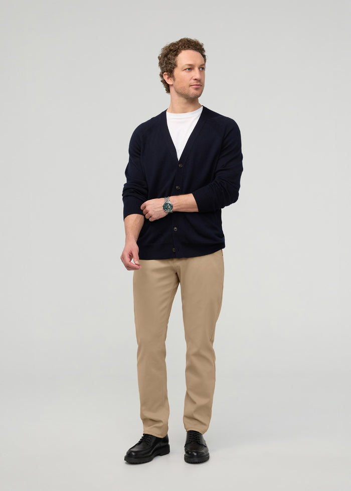 Man wearing desert khaki relaxed taper trousers with navy cardigan and white t-shirt.