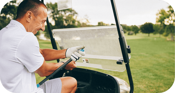 Man sitting in a golf cart on a sunny day outdoors holding a wellness recovery tool named RAD ROD | RAD, designed for muscle relief and body care.