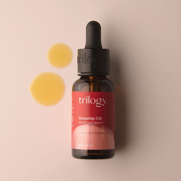 Trilogy Rosehip Oil bottle with dropper on a beige background.