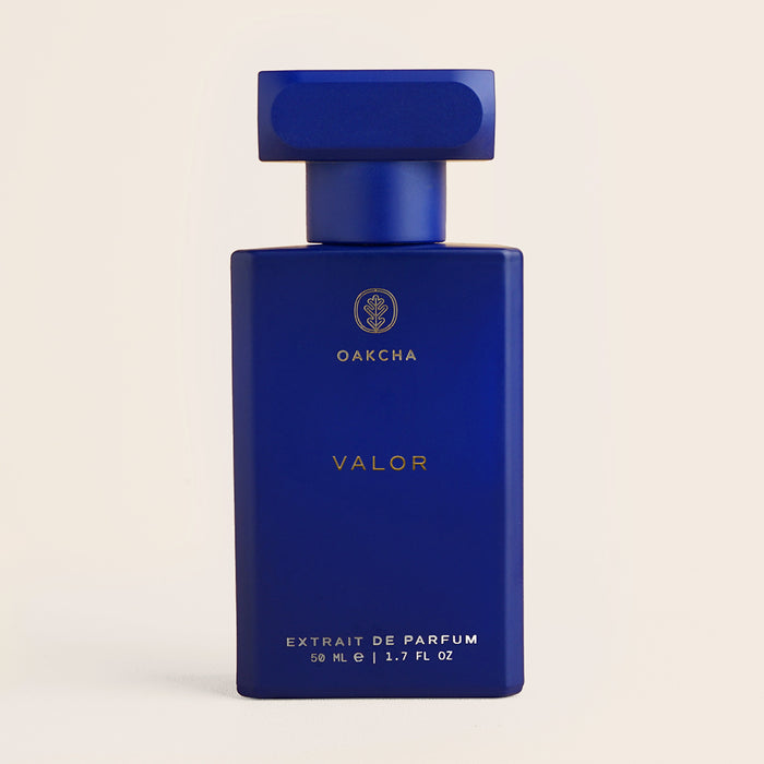 Front view of Valor extrait de parfum bottle showcasing a matte cobalt blue rectangular bottle with gold logo on a light beige background